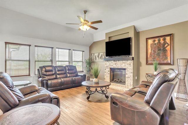 living room with vaulted ceiling, a fireplace, ceiling fan, and light hardwood / wood-style floors