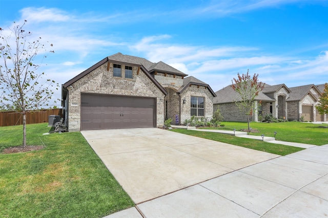 french country home featuring a garage, central AC unit, and a front yard