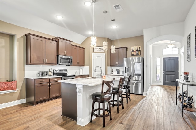 kitchen featuring light hardwood / wood-style floors, light stone countertops, appliances with stainless steel finishes, decorative light fixtures, and sink