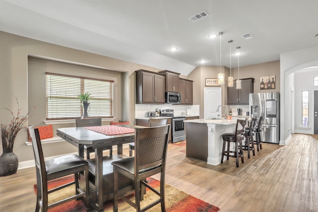 dining space featuring sink, light hardwood / wood-style flooring, and lofted ceiling