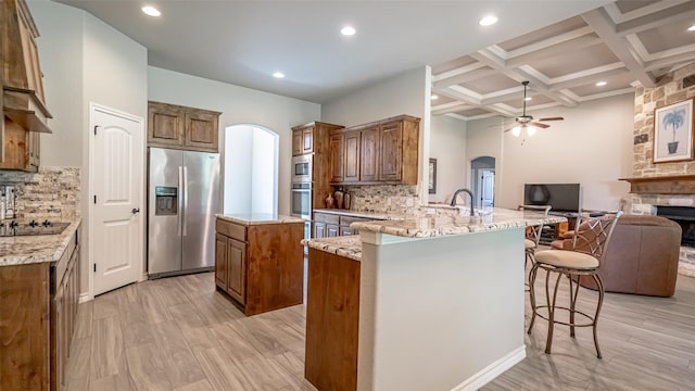 kitchen featuring beam ceiling, coffered ceiling, tasteful backsplash, and stainless steel appliances