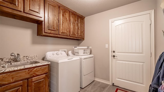 laundry room featuring sink, light hardwood / wood-style flooring, cabinets, and independent washer and dryer