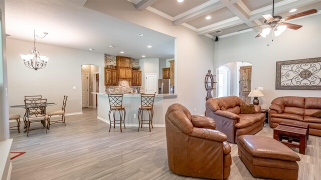 living room with ceiling fan with notable chandelier, beam ceiling, light hardwood / wood-style floors, and coffered ceiling