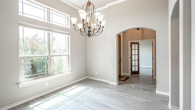 unfurnished room featuring plenty of natural light, crown molding, an inviting chandelier, and a towering ceiling