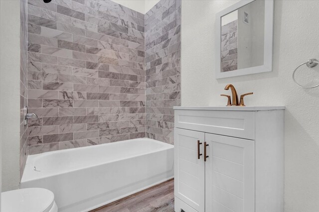 bathroom with vanity, wood finished floors, tub / shower combination, toilet, and a textured wall