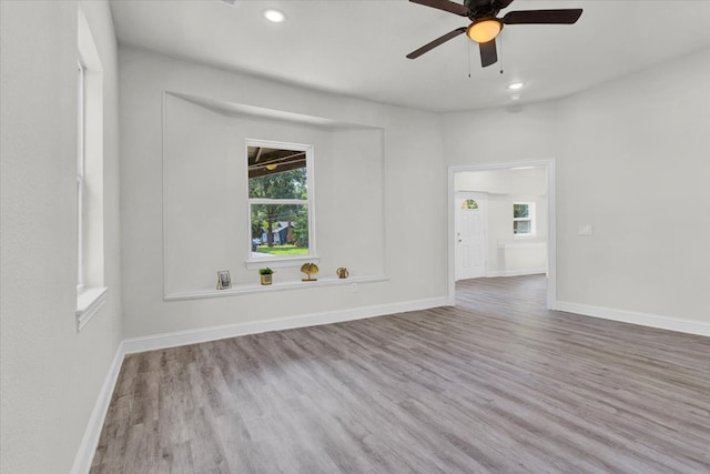 empty room with ceiling fan and light hardwood / wood-style flooring