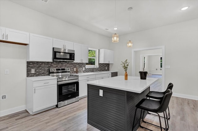 kitchen featuring a breakfast bar, stainless steel appliances, decorative backsplash, white cabinets, and a center island