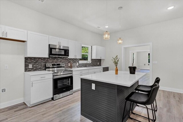 254 19th St SE, Paris, TX 75460 - kitchen with stainless steel appliances, white cabinets, a kitchen breakfast bar, decorative backsplash, and light countertops