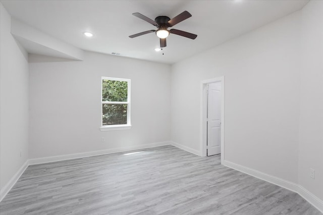 empty room featuring ceiling fan, visible vents, baseboards, and wood finished floors