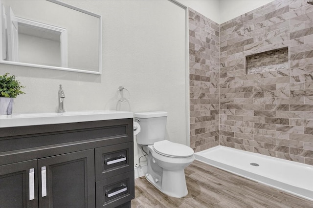 bathroom with a stall shower, toilet, vanity, and wood finished floors