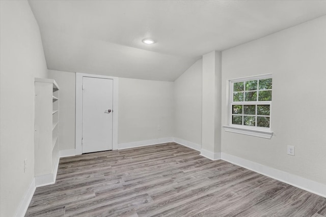 spare room with lofted ceiling, wood finished floors, and baseboards