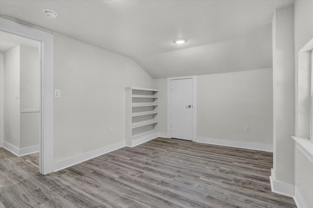 additional living space featuring light hardwood / wood-style floors and vaulted ceiling