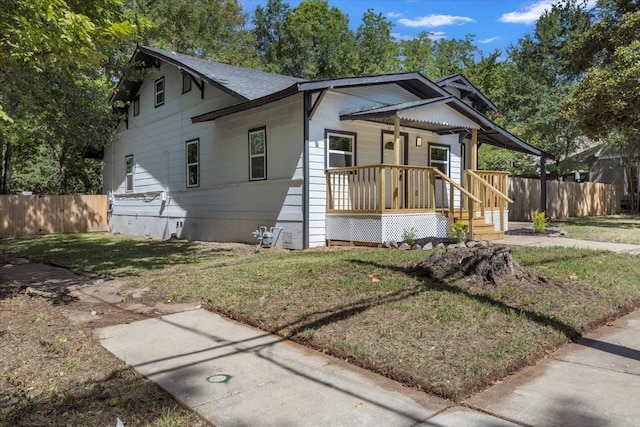 bungalow-style home featuring a porch, a front lawn, and fence