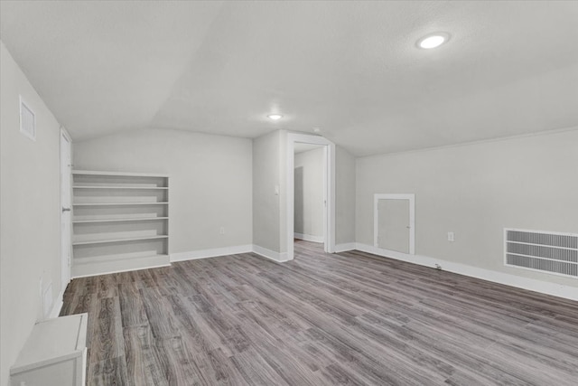 additional living space with light hardwood / wood-style floors and lofted ceiling