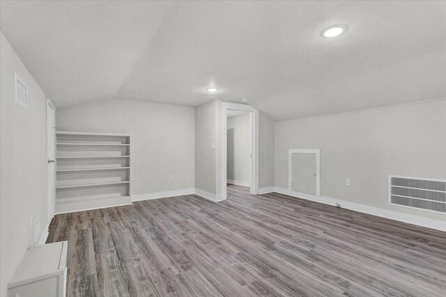 254 19th St SE, Paris, TX 75460 - bonus room featuring vaulted ceiling, wood finished floors, baseboards, recessed lighting, and a textured ceiling