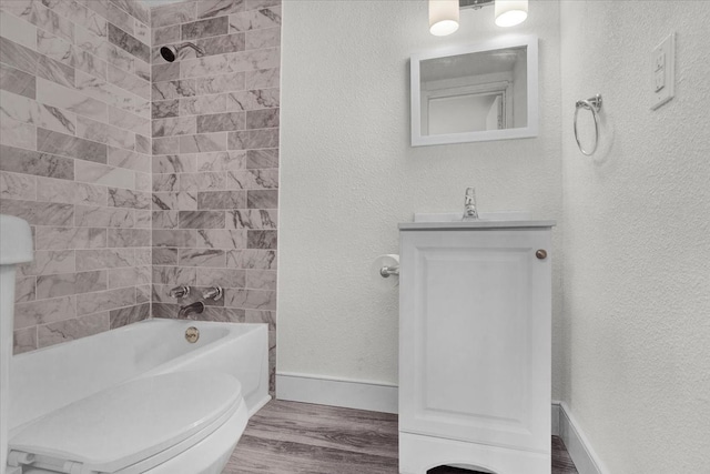 full bath with toilet, wood finished floors, baseboards, bathtub / shower combination, and a textured wall