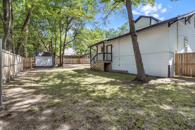 view of yard featuring a storage shed, a fenced backyard, and an outdoor structure