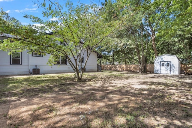 view of yard featuring an outbuilding, a storage unit, and fence