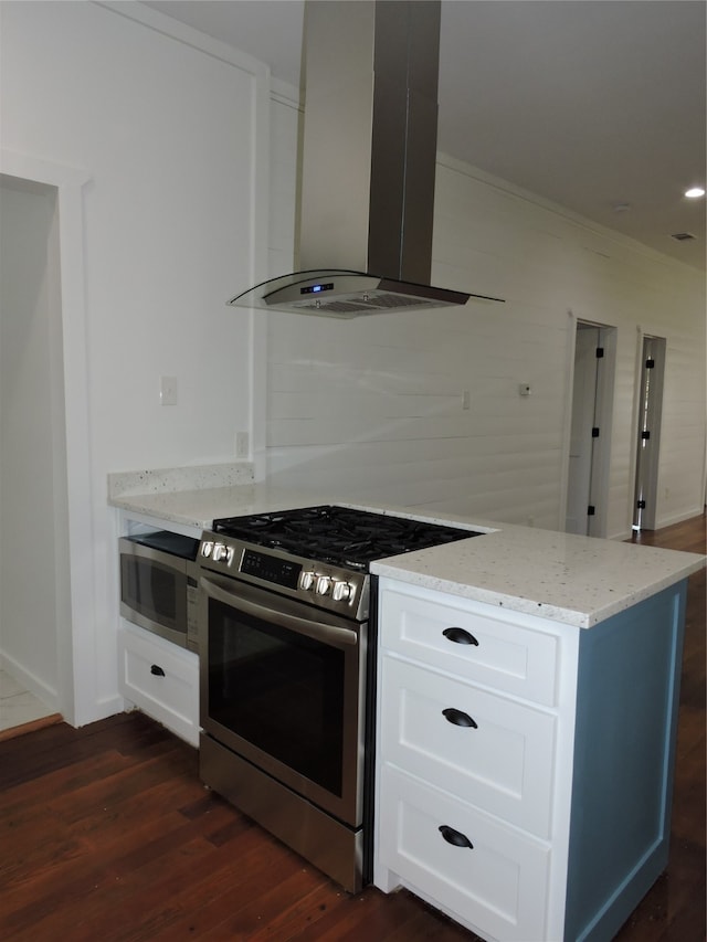 kitchen with appliances with stainless steel finishes, dark hardwood / wood-style floors, light stone countertops, white cabinetry, and wall chimney exhaust hood