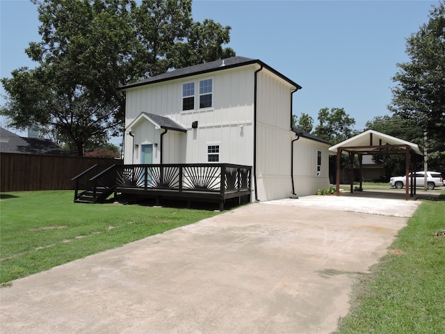 back of house with a carport, a yard, and a deck