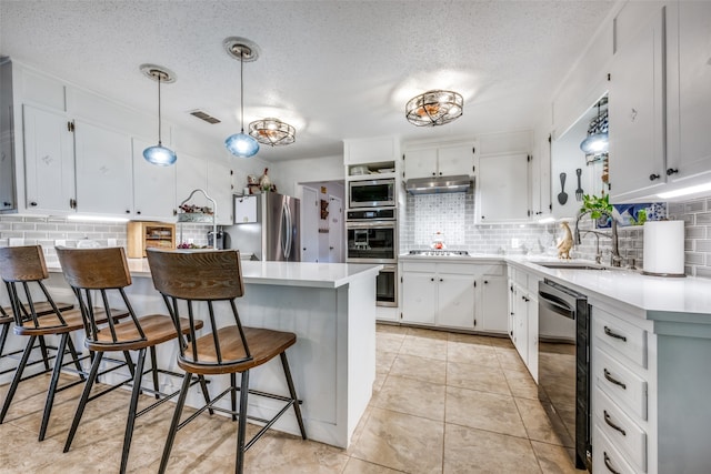 kitchen with tasteful backsplash, stainless steel appliances, sink, decorative light fixtures, and light tile patterned flooring