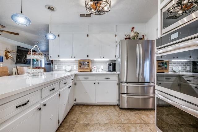 kitchen with light tile patterned flooring, backsplash, stainless steel refrigerator, and white cabinets