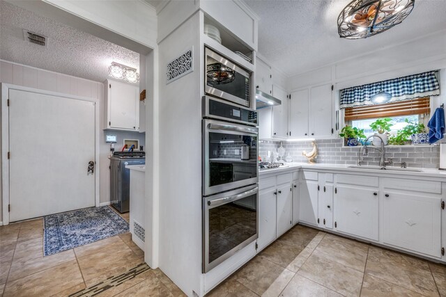 kitchen featuring light tile patterned flooring, white cabinetry, backsplash, stainless steel gas cooktop, and sink