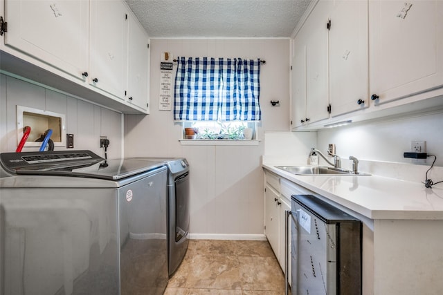 clothes washing area with cabinet space, ornamental molding, a textured ceiling, washer and dryer, and a sink