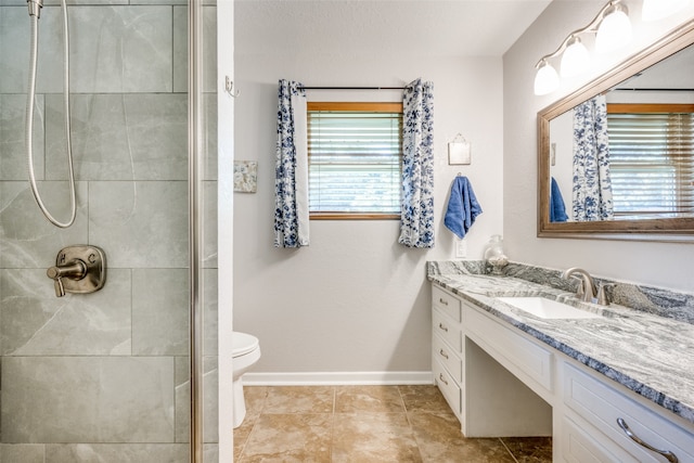 bathroom with tiled shower, vanity, tile patterned flooring, and toilet