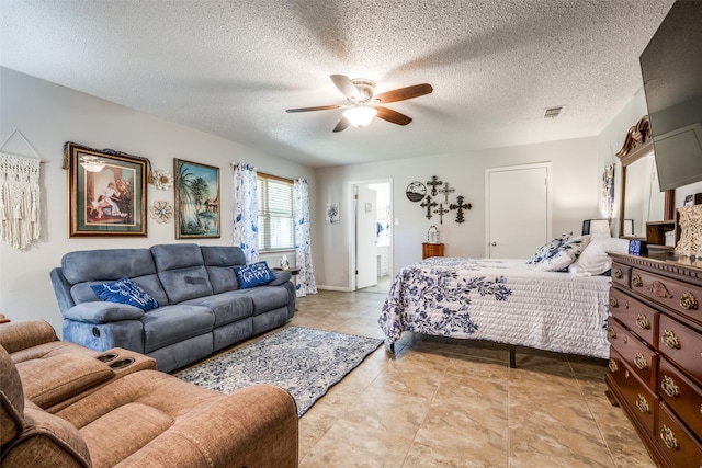 bedroom featuring a textured ceiling, connected bathroom, light tile patterned floors, and ceiling fan