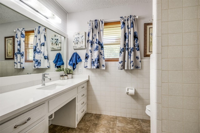 bathroom featuring toilet, tile walls, a textured ceiling, and vanity