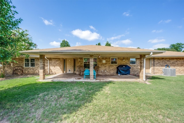 back of property with a yard, brick siding, a patio area, and central air condition unit