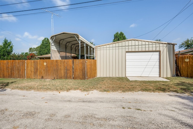 detached garage with a carport and fence