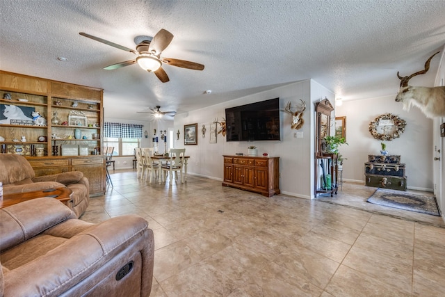 living area with a textured ceiling, ceiling fan, and light tile patterned floors