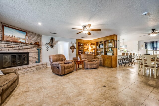 living room featuring light tile patterned flooring, a fireplace, a textured ceiling, and ceiling fan