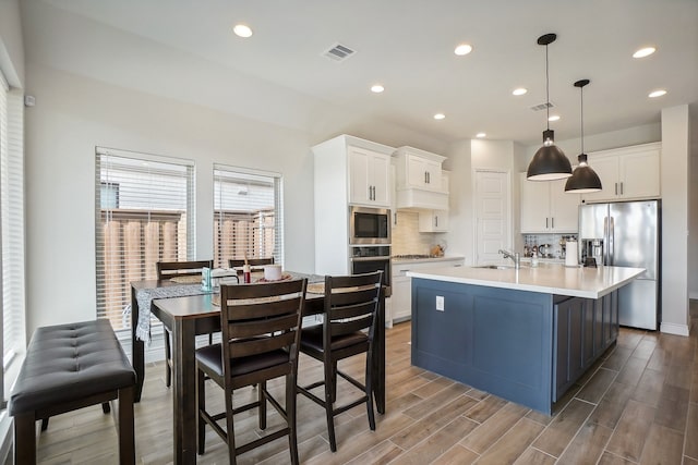 kitchen featuring decorative backsplash, pendant lighting, appliances with stainless steel finishes, and white cabinets