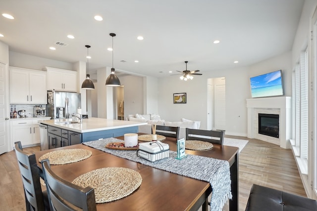 dining area featuring light hardwood / wood-style flooring, sink, and ceiling fan