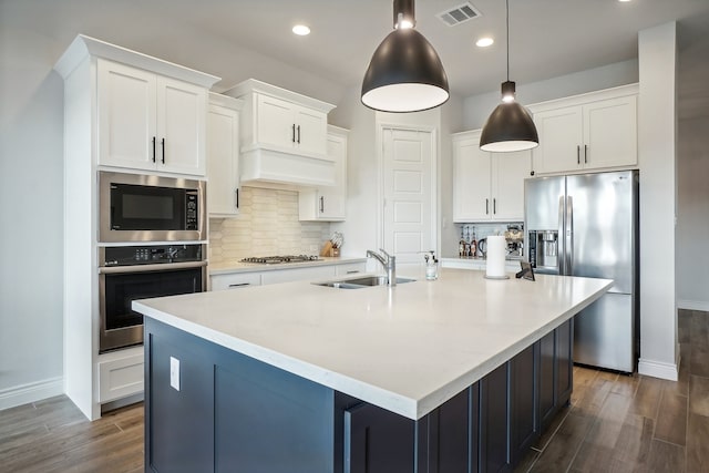 kitchen featuring sink, appliances with stainless steel finishes, a kitchen island with sink, and backsplash