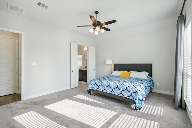 bedroom with light carpet, ensuite bathroom, and ceiling fan