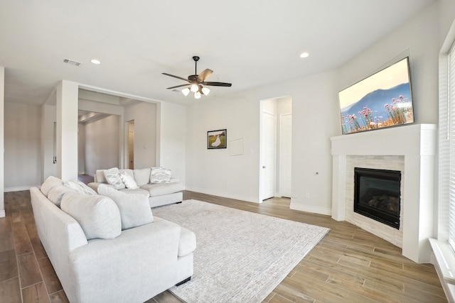 living room featuring a fireplace, ceiling fan, and light hardwood / wood-style floors