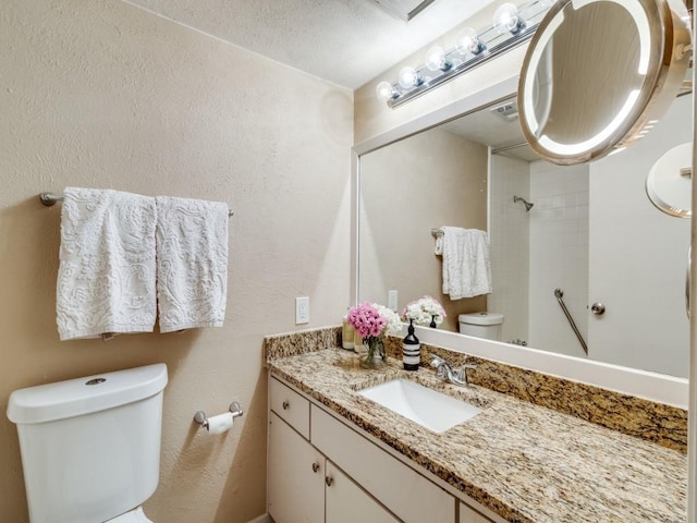 bathroom featuring vanity, a textured ceiling, and toilet