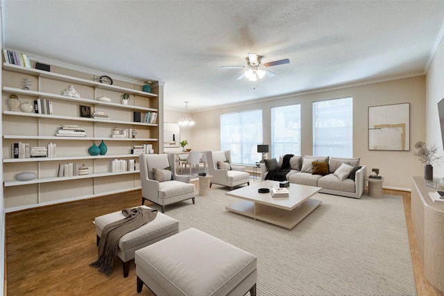 living room with crown molding, ceiling fan with notable chandelier, and hardwood / wood-style flooring