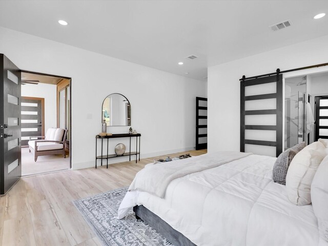 bedroom with light wood-type flooring and a barn door