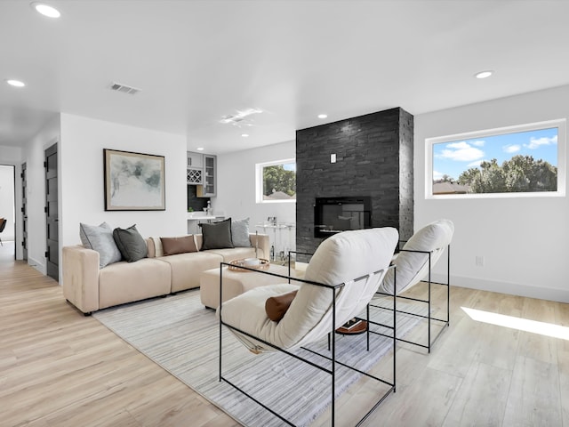 living room featuring a large fireplace and light wood-type flooring