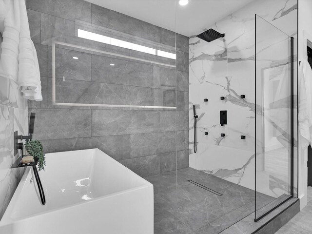 bathroom featuring tile patterned floors, separate shower and tub, and tile walls