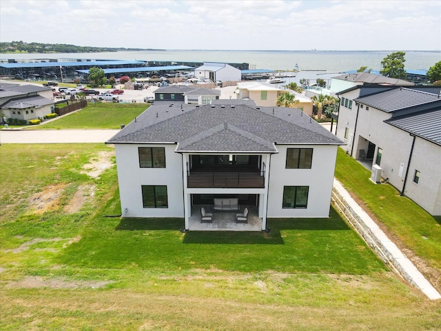 back of property featuring a water view, a yard, and a patio area