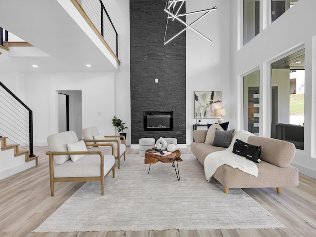 living room with light hardwood / wood-style floors, a large fireplace, and a high ceiling