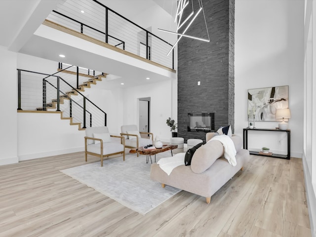 living room featuring a fireplace, light wood-type flooring, and a high ceiling