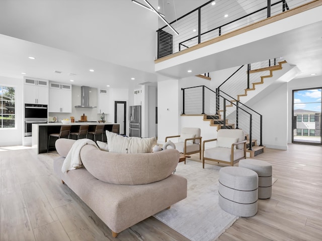 living room with plenty of natural light, a high ceiling, and light hardwood / wood-style floors