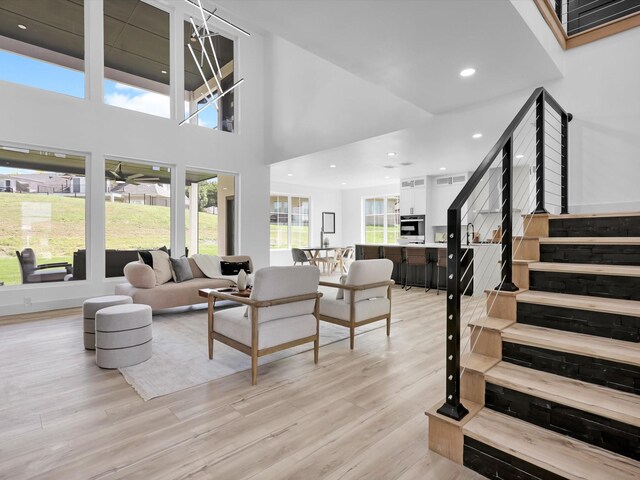 living room with light hardwood / wood-style floors and a towering ceiling